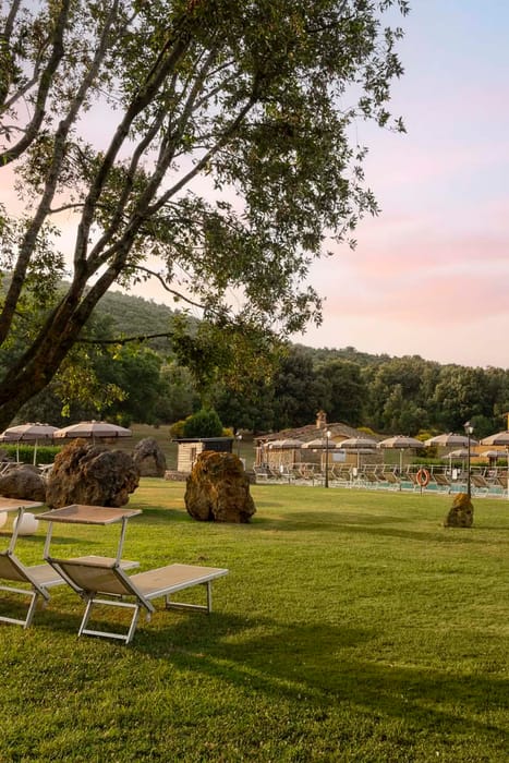 Giardino esterno con piscina e ombrelloni del Casolare Terre Rosse