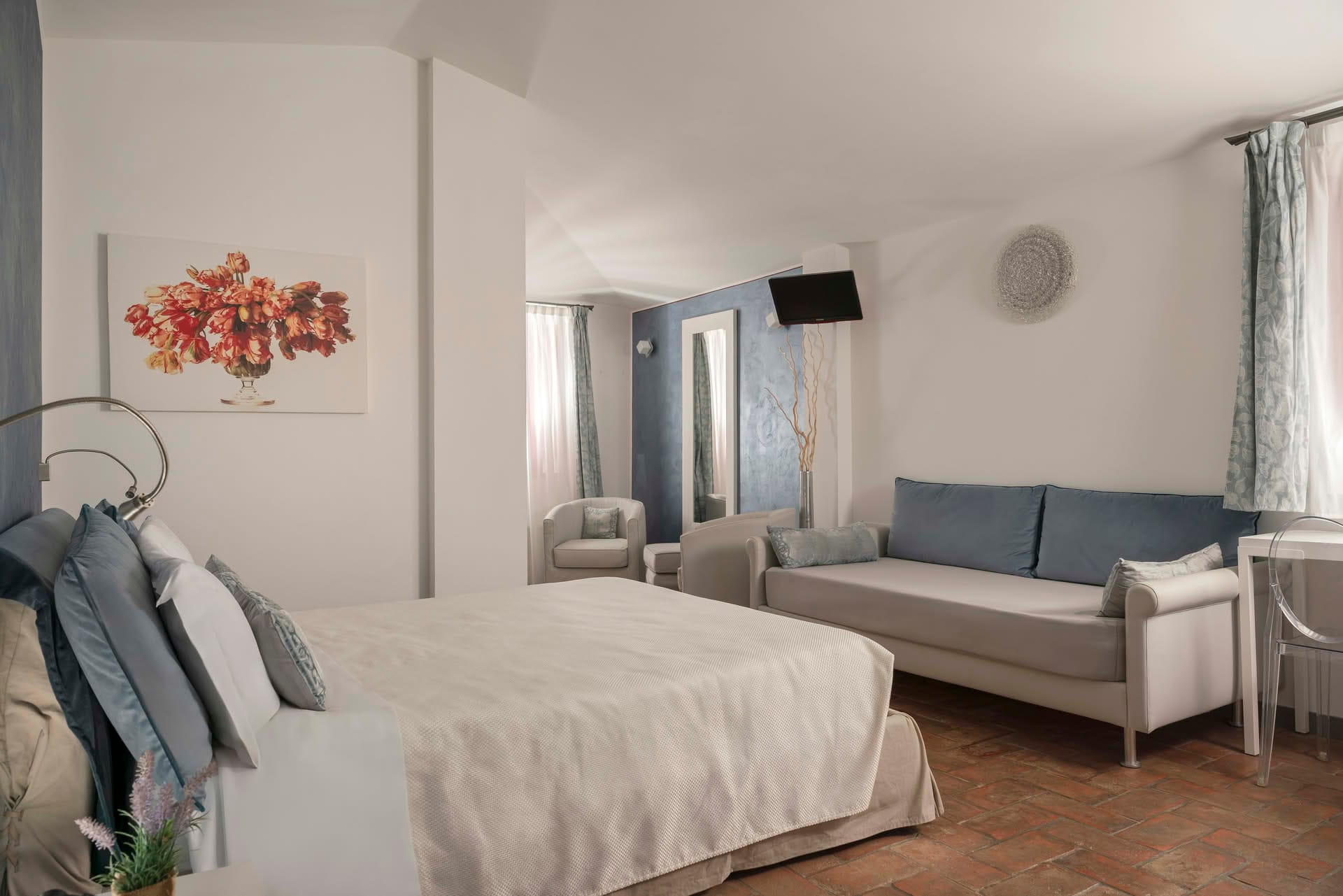 Deluxe Room with double bed, extra bed, and relaxation corner with armchairs