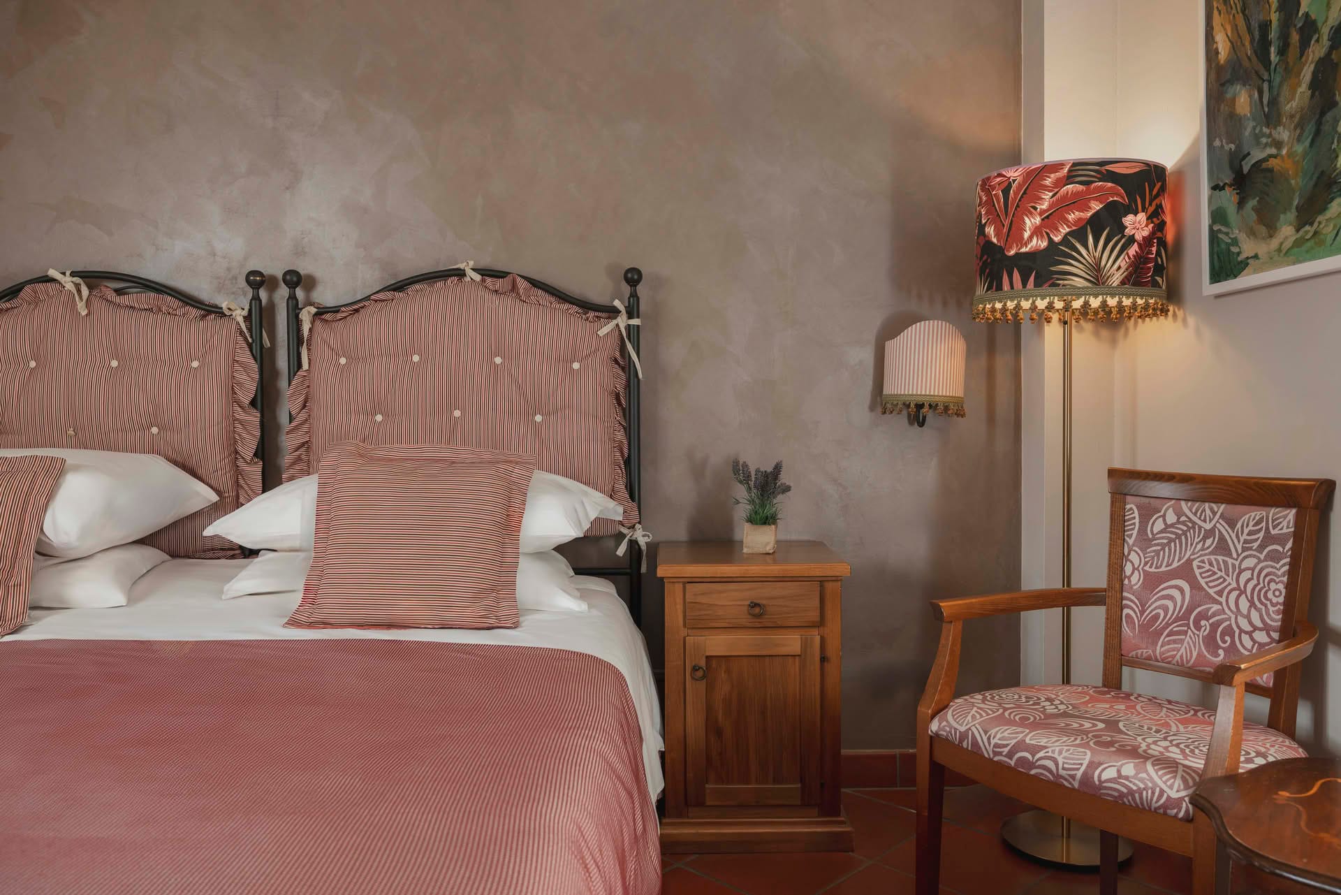 Detail of the double bed with bedside table in the Classic Room at Casolare Terre Rosse